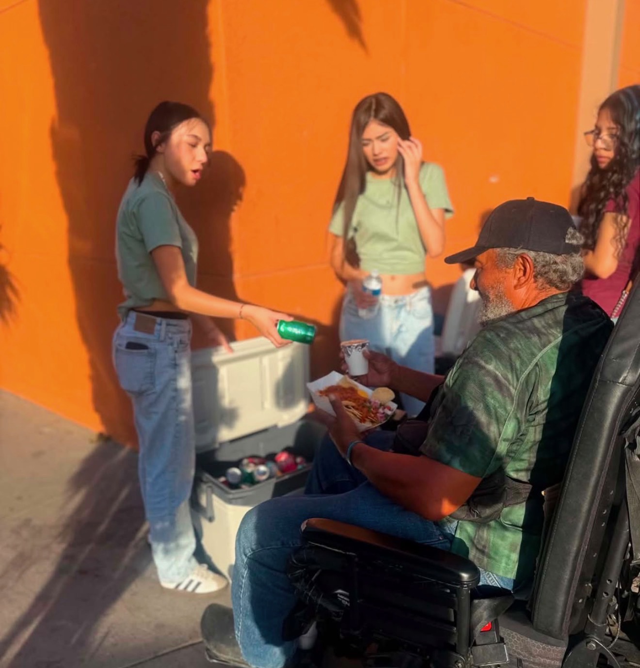 A young volunteer handing a drink to a guest in a wheelchair