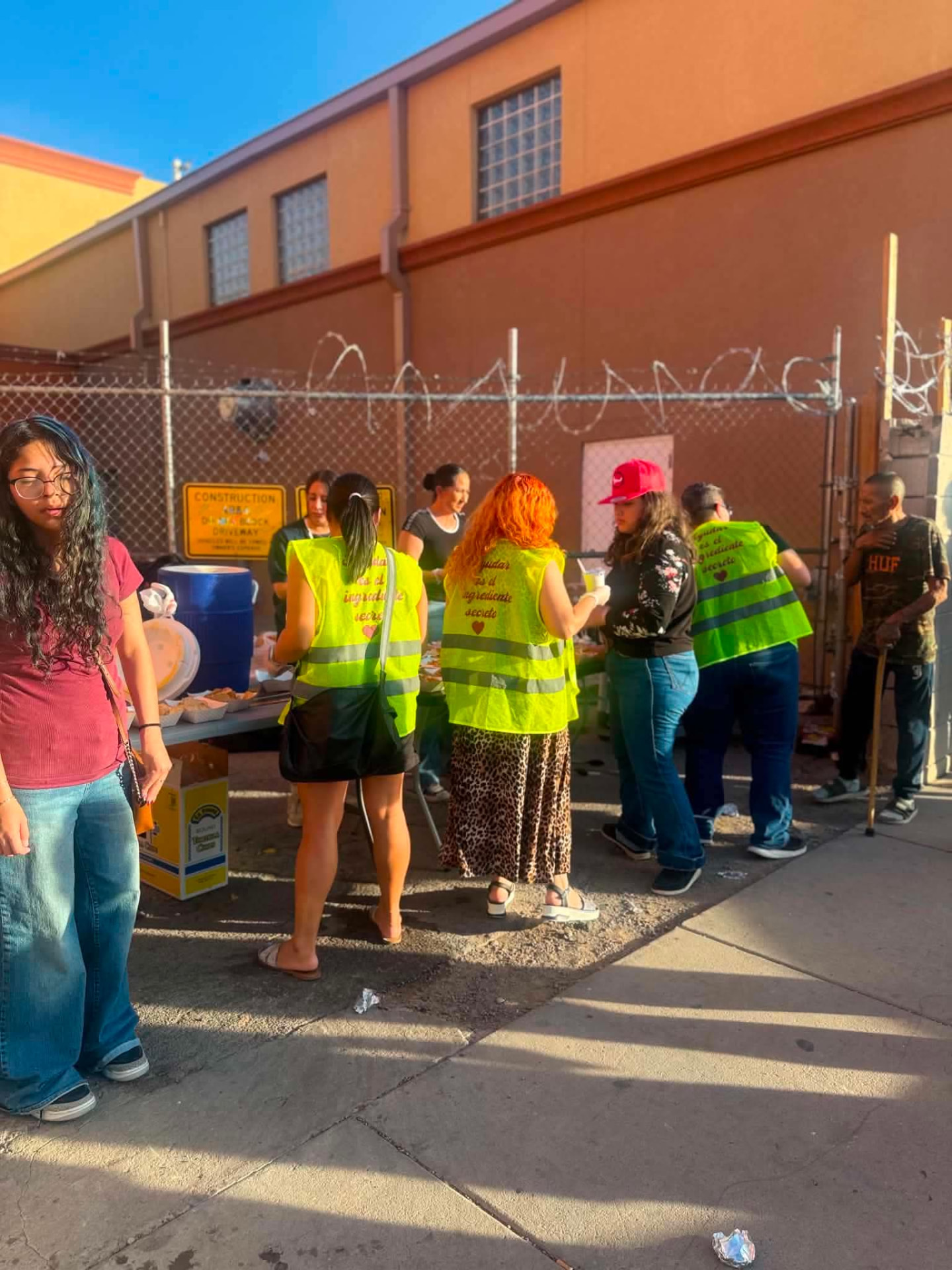 Volunteers in safety vests handing out meals on the sidewalk