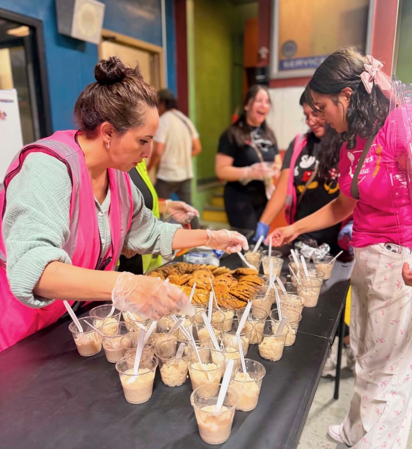 Volunteers setting out cups of dessert and cookies for guests