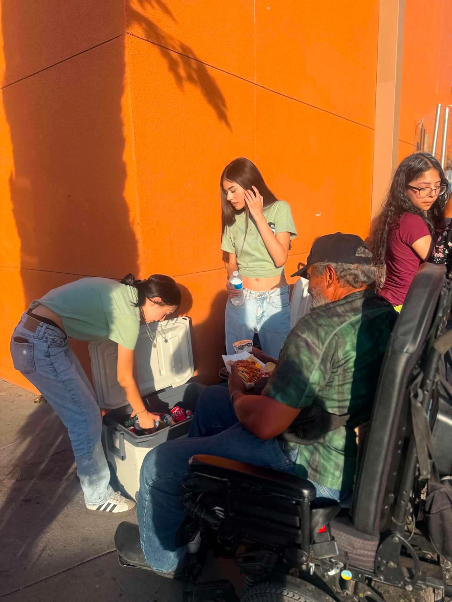 Volunteers handing a meal to a neighbor in a wheelchair